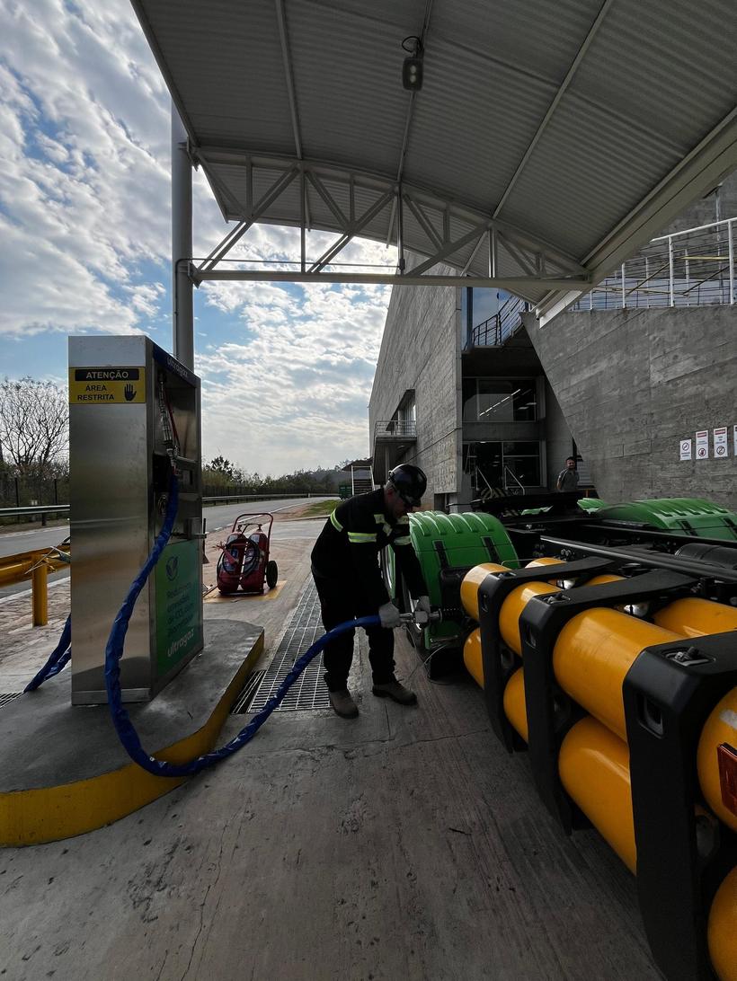Técnico com EPI conectando mangueira de abastecimento em caminhão John Deere