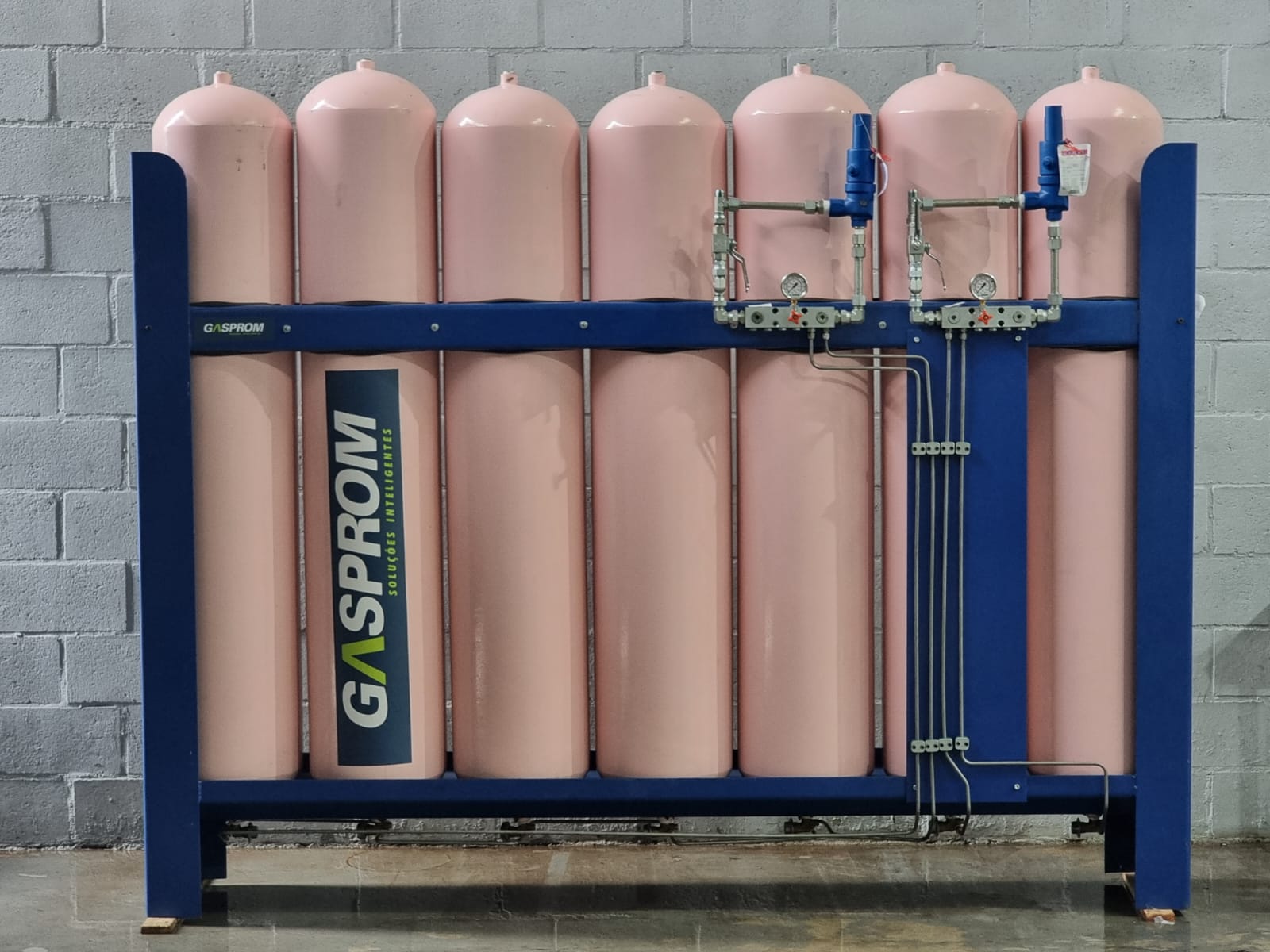 Banco de cilindros de armazenagem de GNC com estrutura azul e marca Gasprom na fábrica